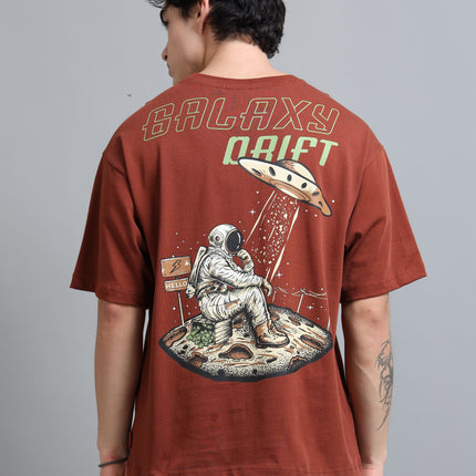 Person wearing a brown t-shirt with a space-themed design and 'Galaxy Drift' text.