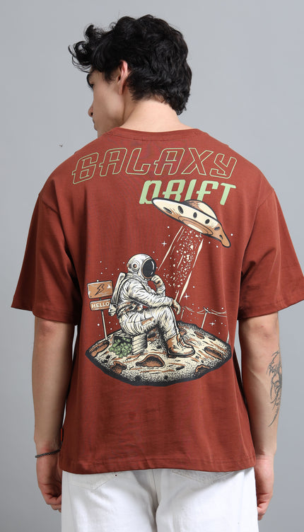 Person wearing a brown t-shirt with a space-themed design and 'Galaxy Drift' text.