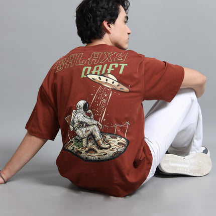 Person wearing a brown t-shirt with space-themed design and text on a gray background
