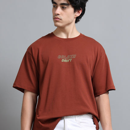 Person wearing a brown t-shirt with text on a gray background